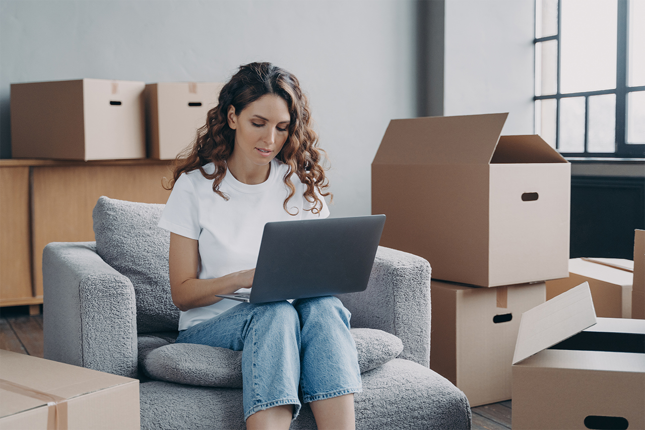 woman-working-on-a-laptop-in-a-room-with-moving-boxes-in-the-background