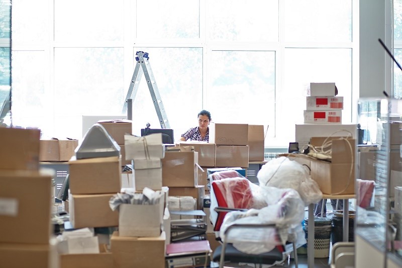 Person-working-in-cluttered-office-surrounded-by-boxes-ladder