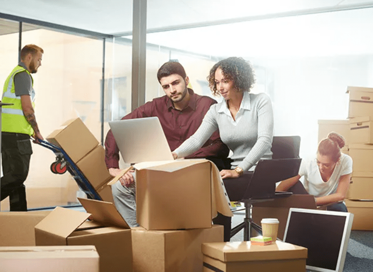 Two-people-working-in-office-boxes-laptops-setting-up