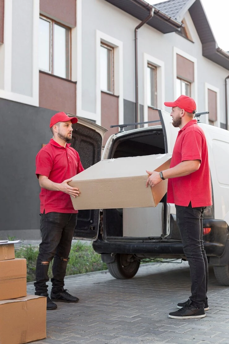 delivery-workers-red-uniforms-caps-carrying-large-box-van-open-back-building-background