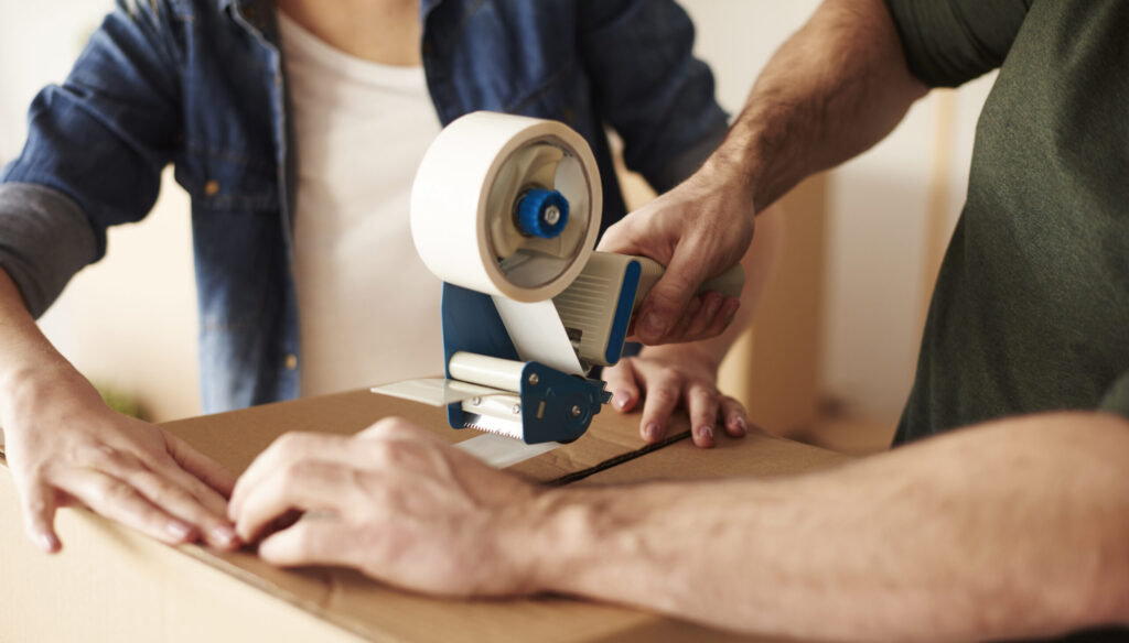 close-up-human-hands-sticking-cartons-scaled